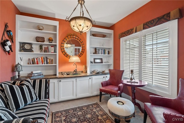 living area featuring built in shelves and light colored carpet