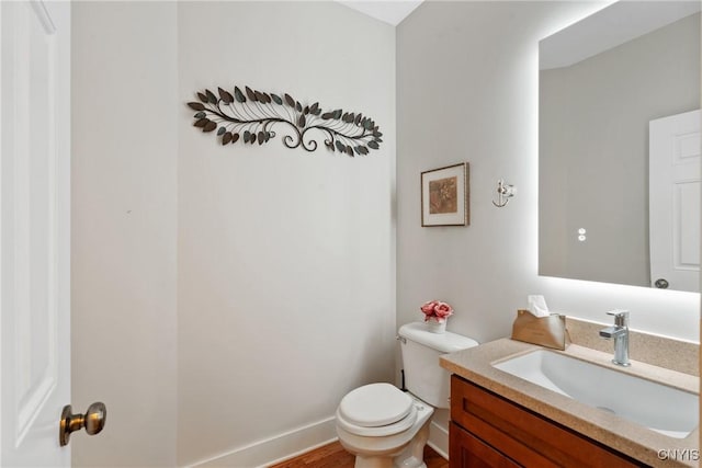 bathroom featuring baseboards, vanity, and toilet