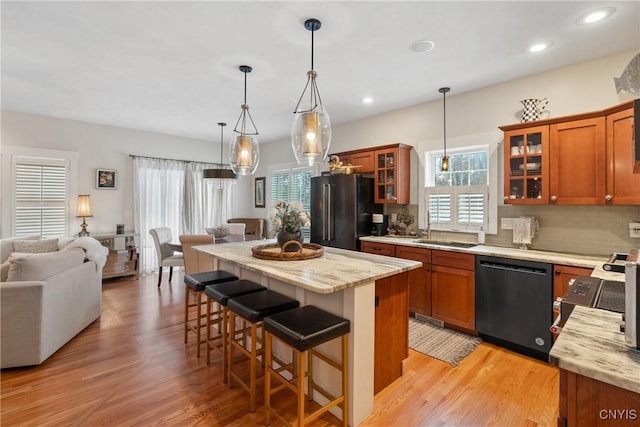 kitchen with dishwasher, high quality fridge, brown cabinetry, and open floor plan