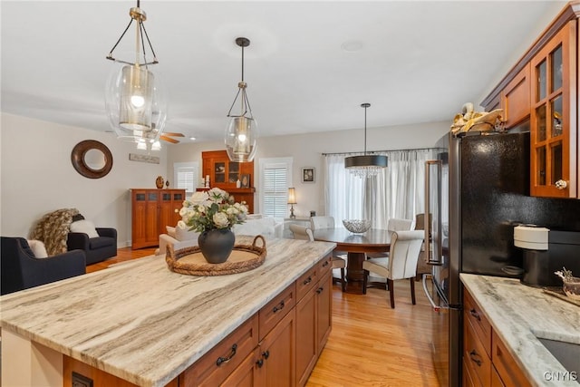 kitchen featuring a kitchen island, glass insert cabinets, brown cabinetry, and open floor plan