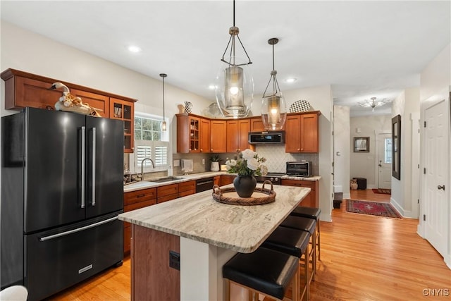 kitchen featuring high quality fridge, a sink, black dishwasher, brown cabinets, and stainless steel microwave