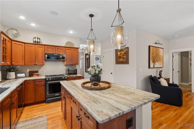 kitchen featuring light wood-style flooring, electric range, backsplash, light stone countertops, and stainless steel microwave