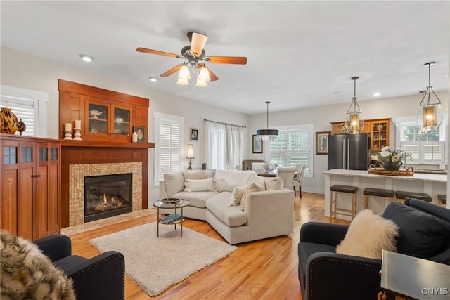 living room with a fireplace with flush hearth, recessed lighting, ceiling fan, and light wood-style flooring