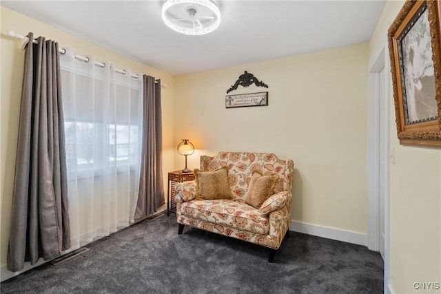 sitting room with baseboards and dark colored carpet