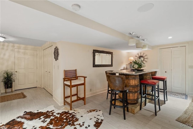 dining area featuring light wood-type flooring, a dry bar, baseboards, and recessed lighting