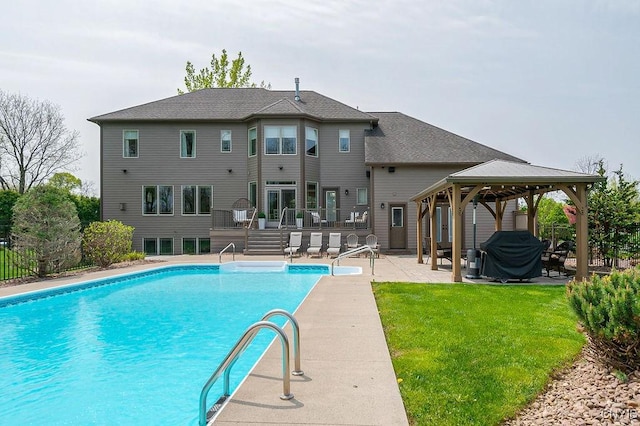 view of swimming pool featuring a patio, a gazebo, a yard, a wooden deck, and a fenced in pool