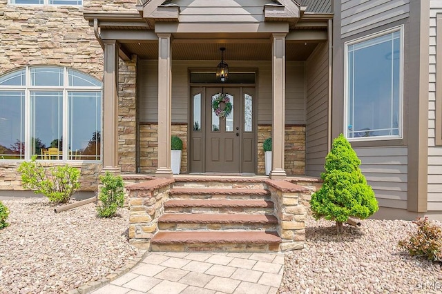 view of exterior entry featuring covered porch and stone siding