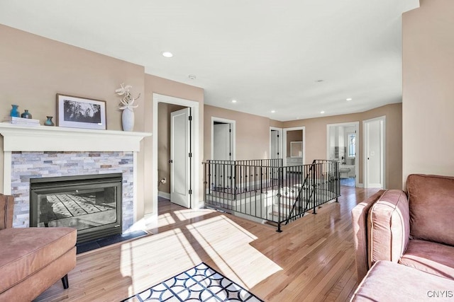 living room featuring a fireplace, baseboards, wood finished floors, and recessed lighting