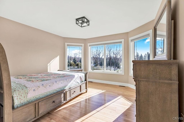 bedroom featuring visible vents, light wood-style flooring, and baseboards