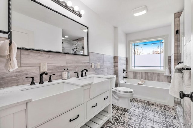 full bathroom with double vanity, toilet, tile patterned floors, a washtub, and tile walls