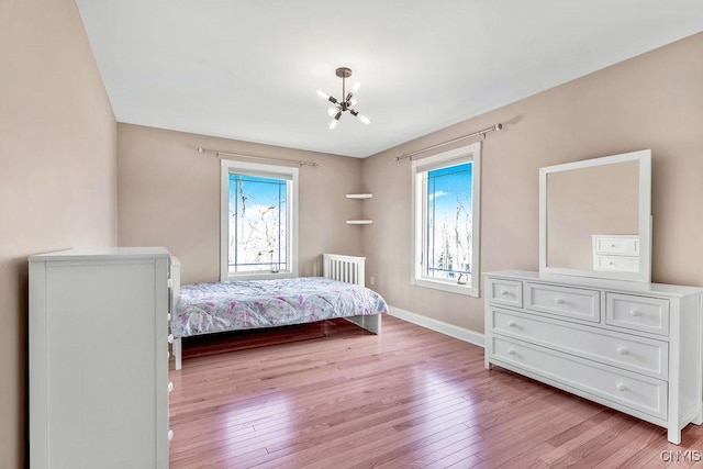 bedroom with light wood-type flooring, baseboards, and a notable chandelier