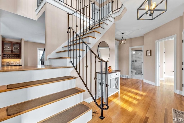 stairway with a chandelier, visible vents, baseboards, and wood finished floors