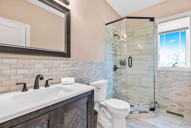 bathroom with visible vents, toilet, vanity, a shower stall, and tile walls