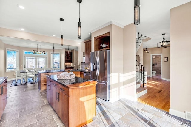 kitchen with pendant lighting, decorative backsplash, appliances with stainless steel finishes, a peninsula, and baseboards