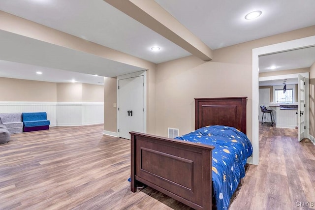 bedroom featuring a wainscoted wall, wood finished floors, visible vents, and recessed lighting