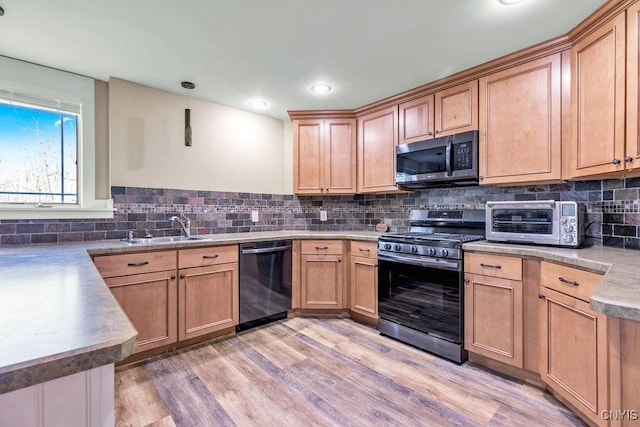 kitchen featuring a toaster, light wood finished floors, tasteful backsplash, appliances with stainless steel finishes, and a sink