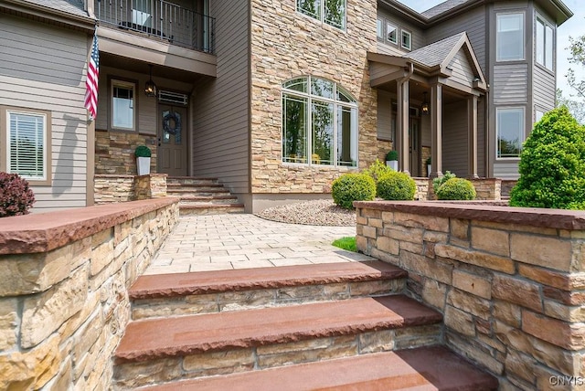 entrance to property featuring stone siding and a balcony