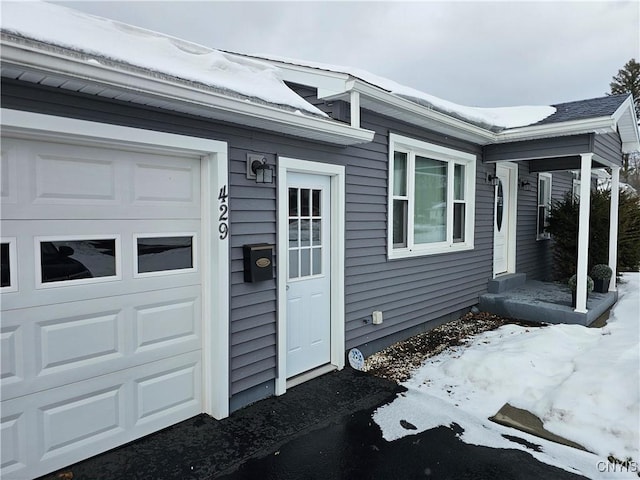 snow covered property entrance with a garage