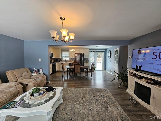 living room featuring baseboards, dark wood finished floors, and a notable chandelier