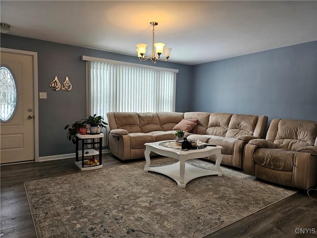 living area with dark wood-type flooring, a notable chandelier, and baseboards