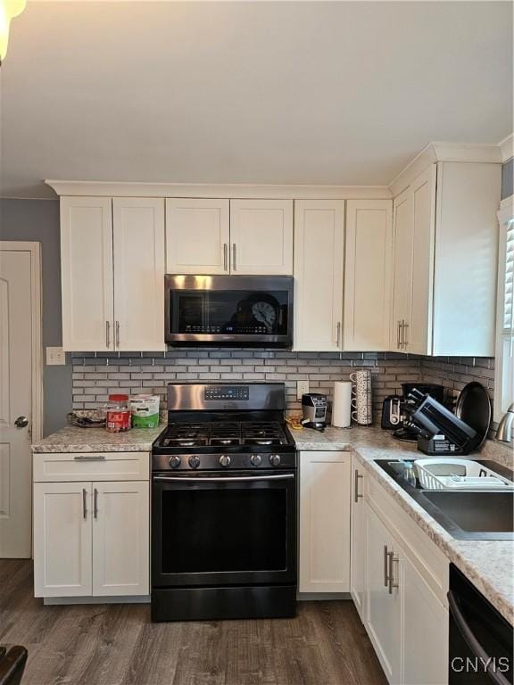 kitchen with black appliances, tasteful backsplash, white cabinets, and dark wood-type flooring