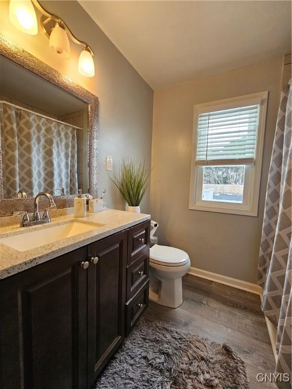 bathroom featuring toilet, vanity, wood finished floors, a shower with curtain, and baseboards