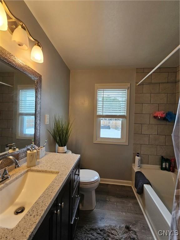 full bathroom with a healthy amount of sunlight, toilet, wood finished floors, and vanity