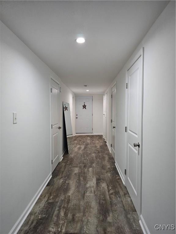 corridor with dark wood-type flooring, recessed lighting, and baseboards