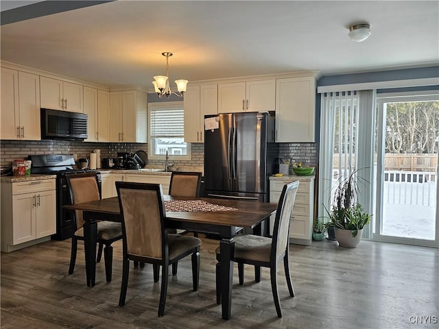 kitchen with dark wood-style floors, backsplash, freestanding refrigerator, black gas stove, and a chandelier