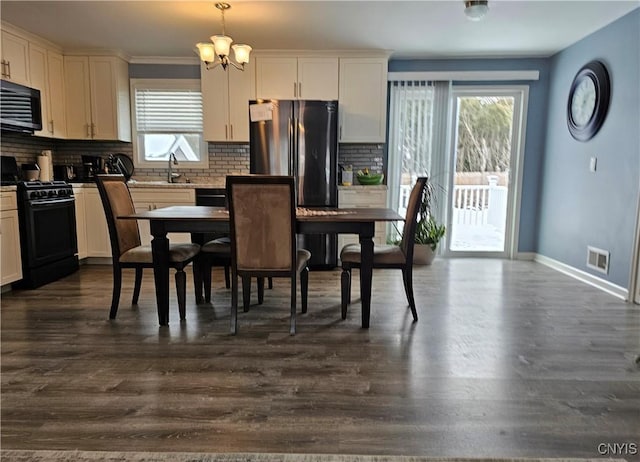 dining space featuring dark wood-style flooring, visible vents, a notable chandelier, and baseboards