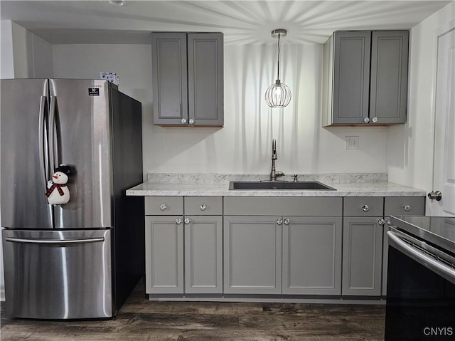 kitchen with dark wood-style floors, stainless steel appliances, a sink, and gray cabinetry