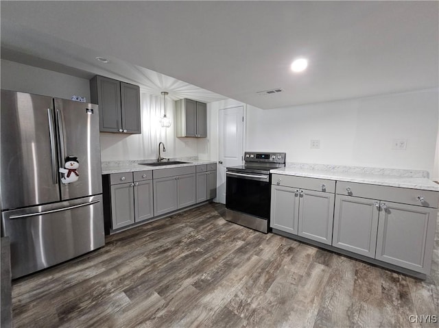 kitchen with gray cabinetry, stainless steel appliances, a sink, visible vents, and dark wood-style floors