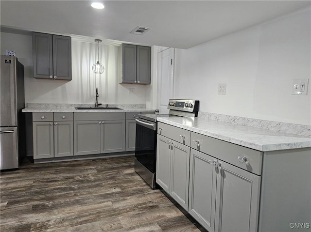 kitchen featuring dark wood finished floors, gray cabinets, stainless steel appliances, and a sink