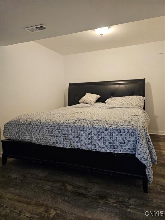 bedroom featuring baseboards, visible vents, and wood finished floors