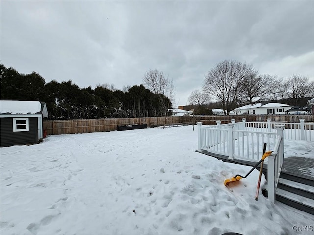 yard layered in snow with an outbuilding, a fenced backyard, and a storage unit