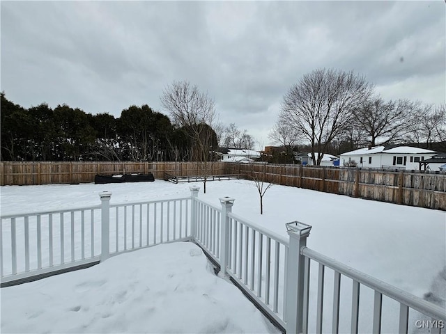 snowy yard with a fenced backyard