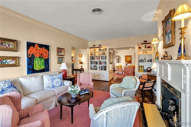 living area featuring a fireplace with flush hearth, wood finished floors, visible vents, and crown molding