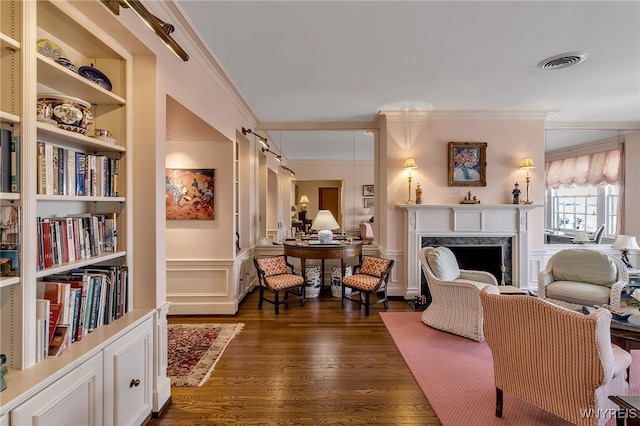 interior space with visible vents, a decorative wall, dark wood-type flooring, a high end fireplace, and ornamental molding