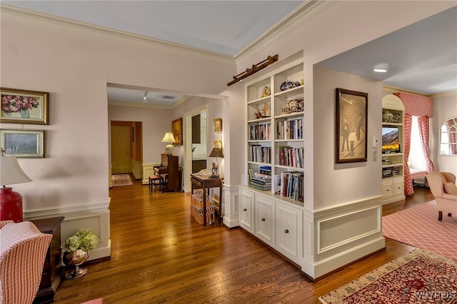 hallway featuring ornamental molding, wainscoting, and dark wood finished floors