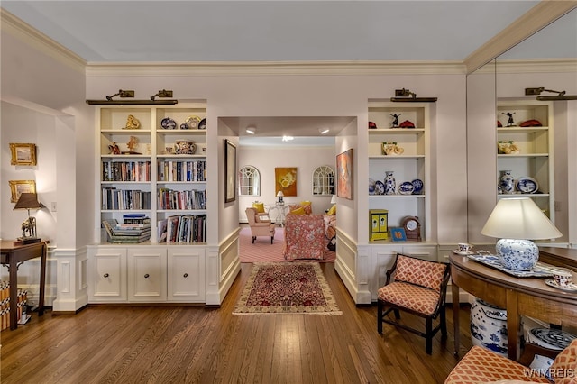 living area with built in features, ornamental molding, and dark wood-type flooring