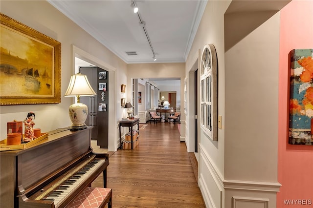 hall with rail lighting, wood finished floors, visible vents, and crown molding