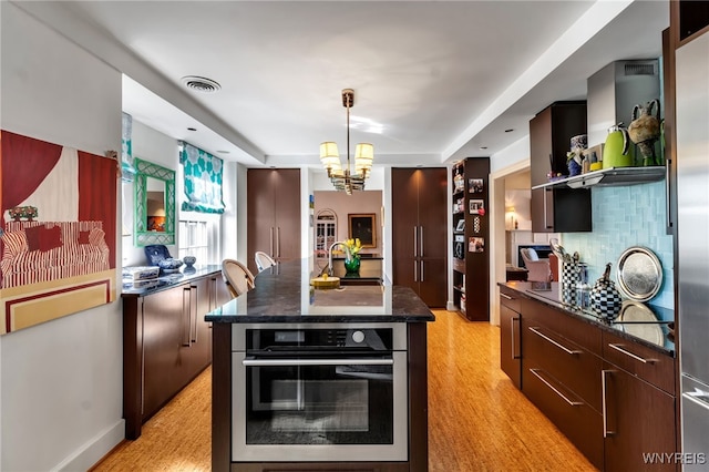 kitchen with visible vents, decorative backsplash, a sink, modern cabinets, and oven