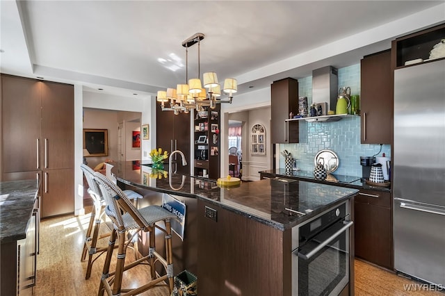 kitchen featuring stainless steel appliances, open shelves, decorative backsplash, wall chimney exhaust hood, and modern cabinets