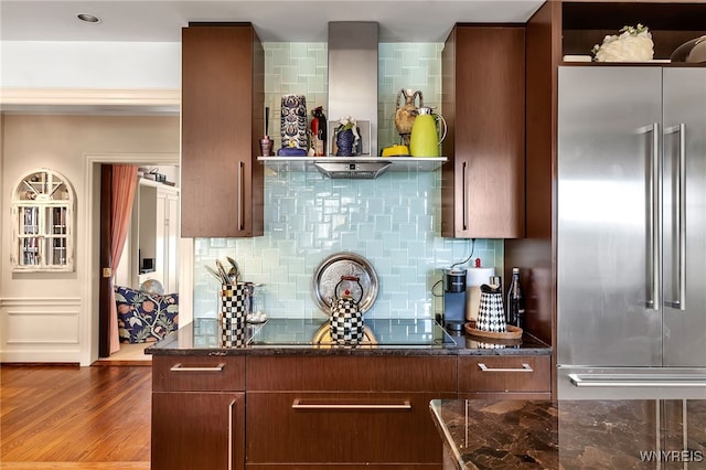 kitchen featuring dark stone counters, high quality fridge, wood finished floors, black electric cooktop, and backsplash