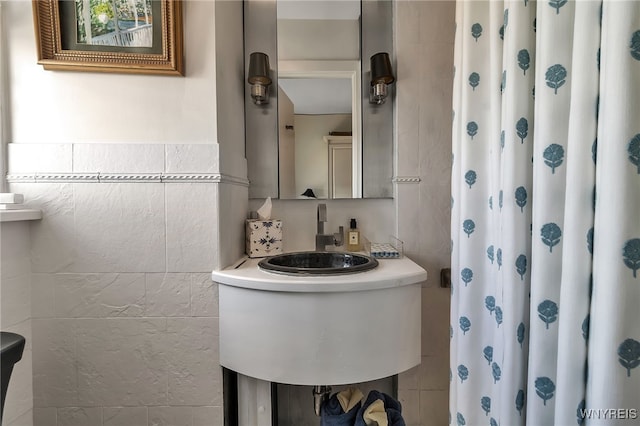 full bathroom with a sink, a shower with curtain, and tile walls