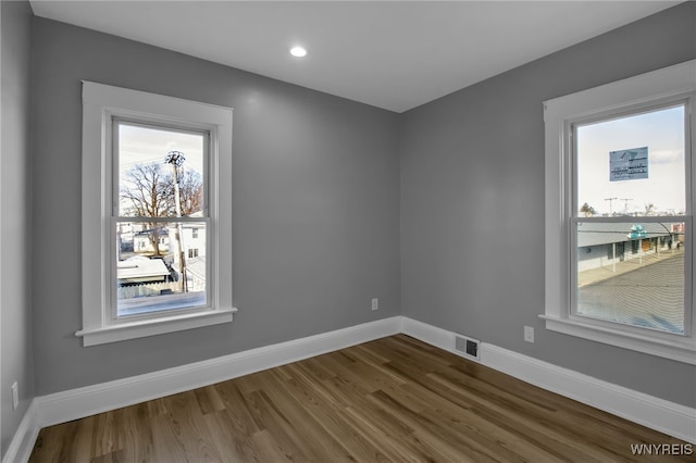 empty room featuring dark wood-type flooring, recessed lighting, visible vents, and baseboards