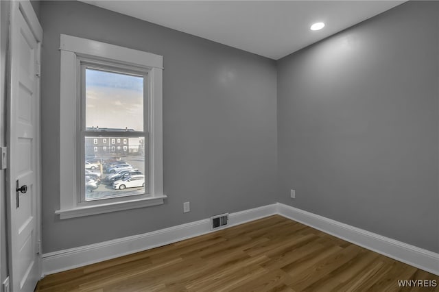 empty room featuring visible vents, baseboards, wood finished floors, and recessed lighting