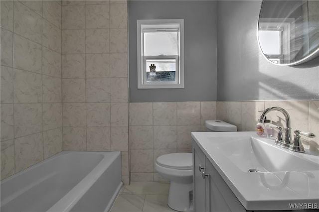 bathroom featuring toilet, a bathing tub, marble finish floor, vanity, and tile walls