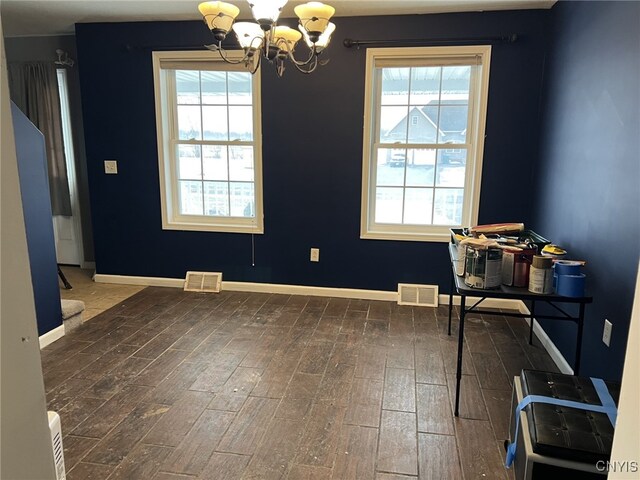 unfurnished dining area featuring baseboards, wood finish floors, visible vents, and a healthy amount of sunlight