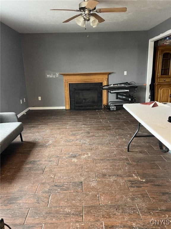 living room featuring a fireplace, a ceiling fan, and baseboards